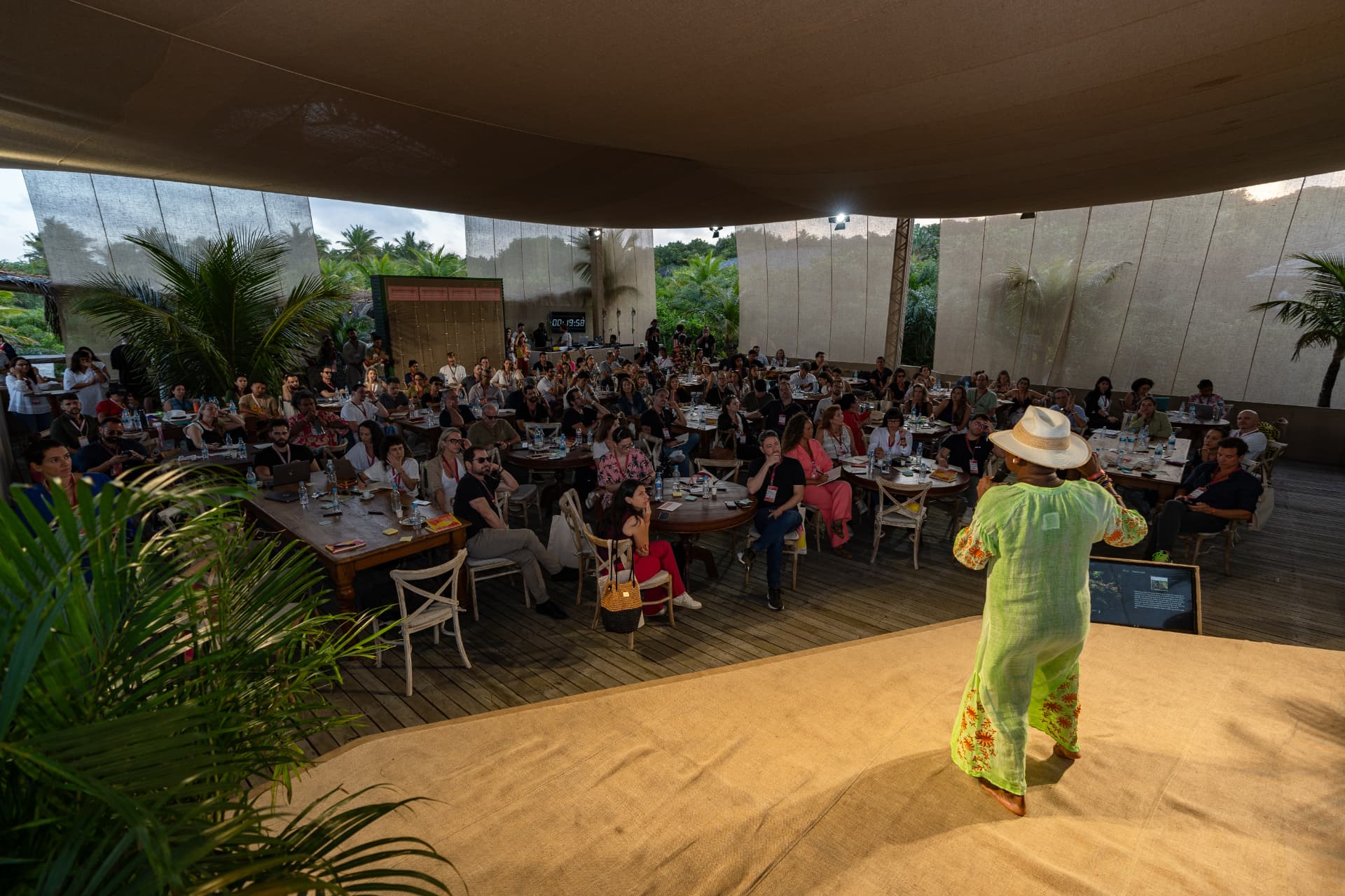Ada Parris on stage at KES, Brazil, seen from behind, facing a full room seated at tables